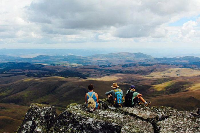 Three hikers sitting on a rock looking out over the highlands
